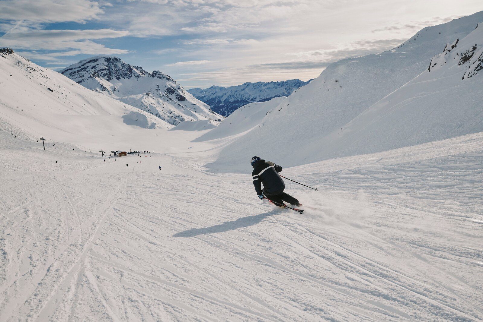 Skieur qui descend une large piste en haute montagne Skieur qui descend une large piste en haute montagne